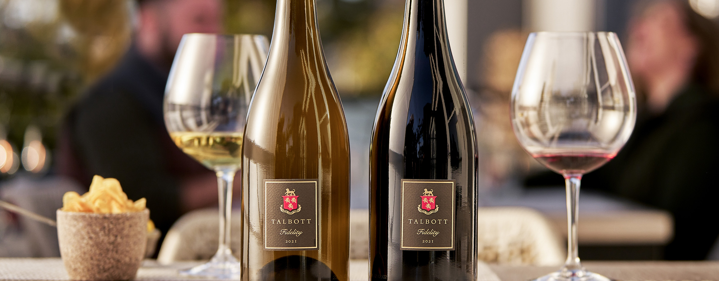 Talbot Fidelity Wines placed on a table with snacks and people in the background.