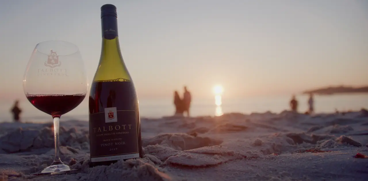 Bottle of Talbott Vineyards wine on the beach at sunset
